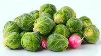 Fresh brussels sprouts and pink radishes on white background, healthy organic vegetables for cooking seasonal dishes and holiday meals.