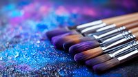Makeup brushes on dark surface with scattered purple and blue glitter powder, professional cosmetic tools arranged in diagonal line with soft focus effect.