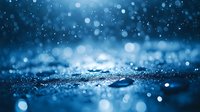 Magical blue bokeh background with glowing sparkles and water drops creating dreamy atmosphere. Defocused lights on dark surface with shallow depth of field.