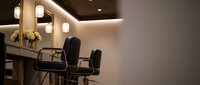 Modern hair salon interior with black styling chairs and warm LED lighting for professional beauty services and hairdressing business.