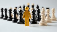 Golden figure stands out among chess pieces representing leadership strategy and business decision making in competitive environment.