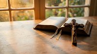 Open bible with wooden cross on rustic table by window with warm sunlight streaming in creating peaceful spiritual atmosphere for prayer and meditation.