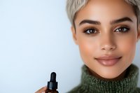 Senior woman with short gray hair and warm brown eyes holding dark serum bottle for skincare, cosmetics, and beauty product marketing campaigns.