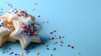 Star-shaped sugar cookies with white icing and colorful sprinkles on blue background, perfect for holiday celebrations and festive dessert photography.