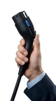 Male hand holding black electric vehicle charging plug with blue LED indicators isolated on white background for automotive and sustainable energy concepts.