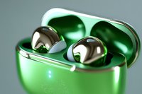 Metallic wireless earbuds in glossy green charging case with chrome finish details, close-up macro photography showing reflective surface and premium design elements.