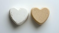 Two heart-shaped bath bombs in white and beige colors on clean background, spa wellness relaxation self-care skincare beauty treatment products isolated.