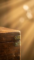 Vintage wooden chest with brass hinges against warm golden bokeh background creating nostalgic atmosphere for antique and heritage themed designs.