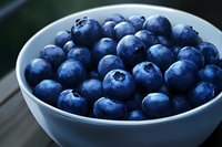Fresh ripe blueberries in white ceramic bowl on wooden surface. Healthy organic superfood berries for breakfast, smoothies and baking recipes.