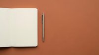 Blank notebook with pen on terracotta background, flat lay composition for business, education, planning, writing projects, and creative workspace design concepts.