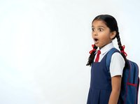 Young South Asian girl in school uniform with surprised expression, wearing navy blue dress, white shirt, and red tie, carrying backpack. Suitable for education, back-to-school campaigns, and student-related content.