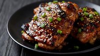 Glazed pork ribs with sesame seeds and herbs on dark plate, barbecue meat dish for restaurant menu and cooking content.