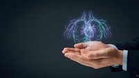 Young adult male professional displaying glowing neon heart anatomy hologram in open palm against dark background. Concept for healthcare, cardiology, medical technology, and digital innovation.