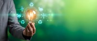 Businessman holding glowing light bulb with green energy icons, renewable power concept on vibrant green background for sustainability projects.
