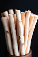 Macro shot of natural bamboo drinking straws in brown holder against dark background, showing sustainable alternative to plastic for eco-friendly lifestyle.