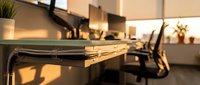 Modern office workspace with wooden desk, ergonomic chair and warm lighting creating productive business environment for professional work.