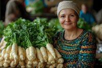Caucasian female farmer in knit cap and patterned sweater displaying fresh harvested parsnips with green tops at local farmers market, genuine smile.