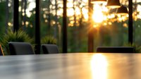 Sunlight streaming through forest creates golden bokeh effect on modern outdoor dining table, capturing serene morning atmosphere in luxury patio setting.