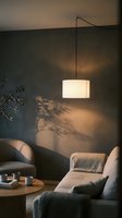 Modern pendant lamp casting warm glow over minimalist living room with gray upholstered armchair, wooden side table, and potted plant creating cozy interior ambiance for home decor and design projects.