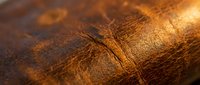 Luxurious brown leather texture with natural grain patterns and warm golden lighting showcasing craftsmanship details for premium fashion and interior design.