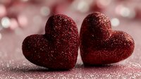 Two red glittery hearts on sparkling surface for Valentine's Day romance love celebration greeting cards wedding anniversary decorations.