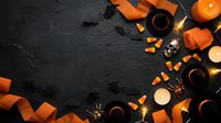 Halloween flat lay with orange ribbons, candy corn, spices and candles on dark slate background. Festive autumn holiday decoration setup for seasonal design projects.