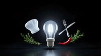 Culinary creativity concept with chef hat, glowing light bulb, crossed utensils, herbs and chili pepper on dark background for restaurant branding.