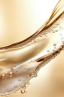 Luxurious golden liquid wave with sparkling bubbles and droplets flowing in smooth curves against soft beige background, creating elegant abstract composition.