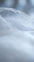 Soft white linen fabric with delicate texture and natural fibers in gentle folds, creating elegant draping effect for textile and fashion design projects.