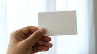 Cropped hand holding blank business card against white background, ready for custom branding and corporate design mockups.