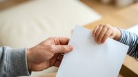 Two people exchanging blank white paper document indoors. Suitable for business, agreement, contract, communication, and professional transaction concepts.