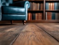 Rustic wooden floor boards with shallow depth of field in cozy home library interior, vintage armchair and bookshelf with old books in soft blur background.