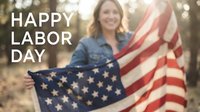 Smiling woman holding American flag outdoors celebrating Labor Day holiday with patriotic pride and joy in natural sunlight setting.