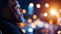 Middle-aged African American man with beard in contemplative profile against warm bokeh city lights background for business and lifestyle concepts.