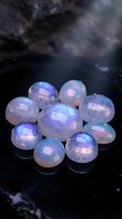 Collection of iridescent opal gemstones with rainbow reflections arranged on dark surface for jewelry making and crystal healing practices.