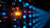 Glowing vintage spiral filament bulb with warm yellow light against blurred blue bokeh background creates atmospheric mood lighting effect.