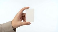 Hand holding blank white business card mockup on light background for branding and corporate identity design projects.