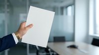 Businessman in dark suit holding blank white paper sheet in modern office environment with blurred background for corporate messaging and branding purposes.