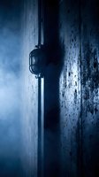 Vintage industrial lamp mounted on weathered concrete wall creates dramatic blue-toned atmosphere with moody lighting and textured surfaces.