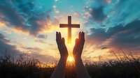 Silhouetted hands reaching toward glowing Christian cross against dramatic sunset sky with vibrant clouds and golden sunburst through grass meadow background.