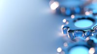 Macro view of water drops on reflective blue metallic surface creating abstract pattern with bokeh light effects and shallow depth of field.
