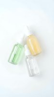 Three glass dropper bottles with colored serums on white background for skincare and cosmetic product photography.