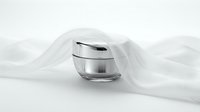 Luxury skincare cream jar with silver cap on white silk fabric for cosmetic product photography and beauty brand marketing campaigns.