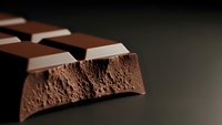 Broken chocolate bar pieces showing rich cocoa texture and aerated interior structure on dark background for confectionery and dessert concepts.