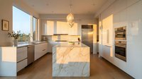 Modern kitchen with marble island, white cabinetry, and pendant lighting. Bright, minimalist design with stainless steel appliances and natural light for home decor and interior design projects.