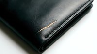 Black leather wallet close-up showing fine craftsmanship and stitching details on white background for business and finance concepts.