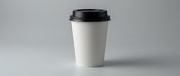 White disposable coffee cup with black lid on neutral background for branding mockup and cafe marketing materials.