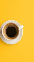 White coffee cup with fresh black coffee on bright yellow background, viewed from above. Minimalist composition with copy space for menu, cafe promotion.