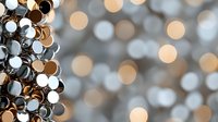Shimmering metallic circles and bokeh lights create abstract festive background with silver and gold tones, soft focus defocused pattern for holiday designs.