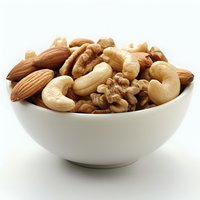 Mixed raw nuts including almonds, cashews, and walnuts in white ceramic bowl on white background, healthy snack food concept for nutrition and diet.